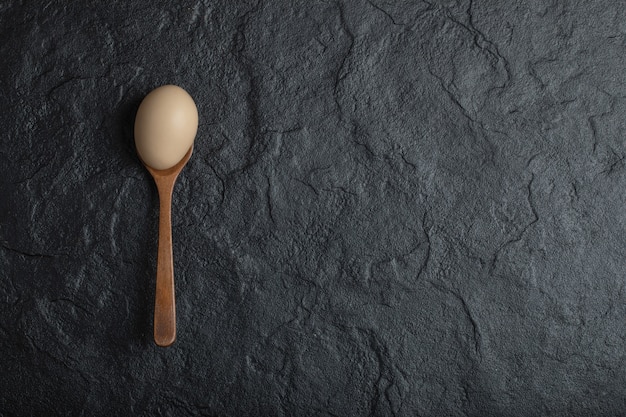 Single organic chicken egg on wooden spoon. 