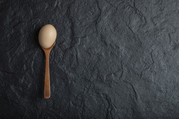 Single organic chicken egg on wooden spoon. 