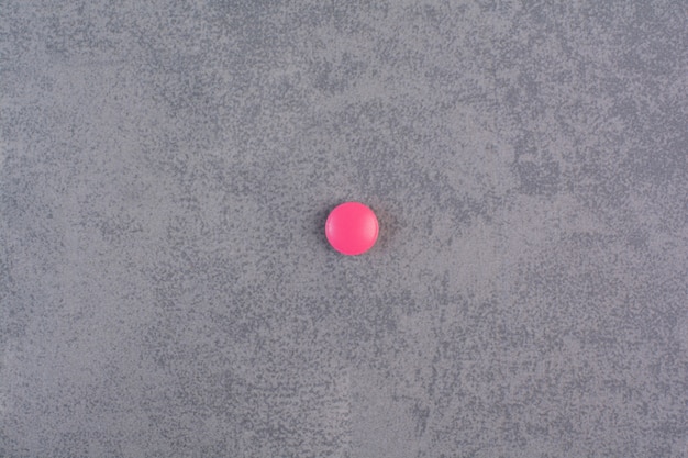 Free photo single pink pill on marble table.