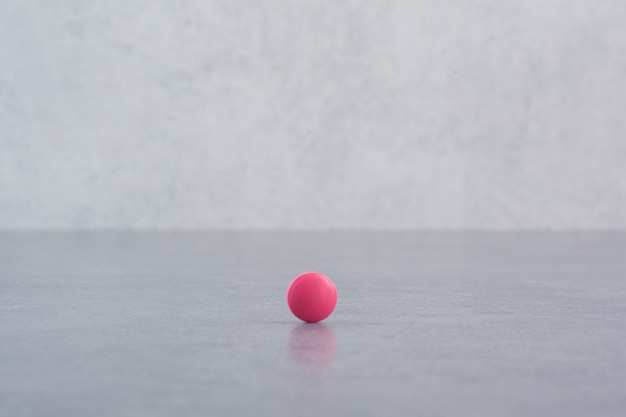 大理石のテーブルの上の単一のピンクの丸薬。