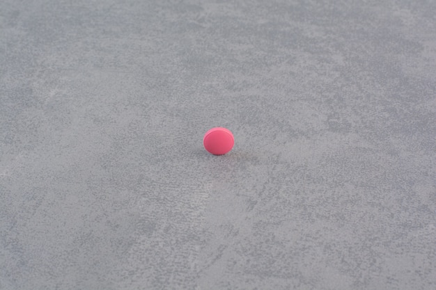 Single pink pill on marble table