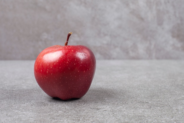 Single red apple on marble surface
