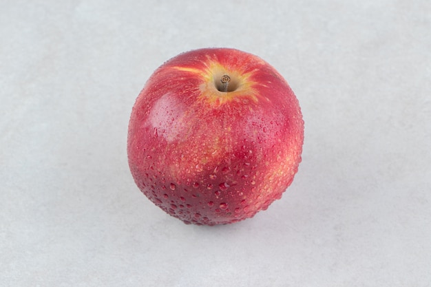 Single red apple on stone table.