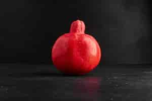 Free photo a single red pomegranate on black space.