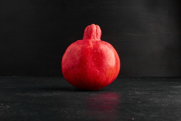 A single red pomegranate on black space. 