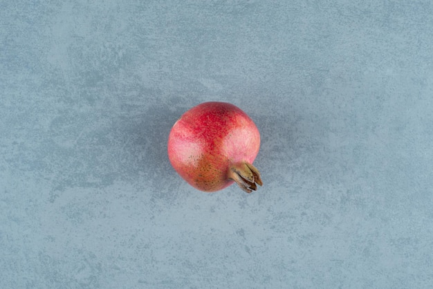 Single red pomegranate on marble.