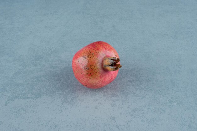 Single red pomegranate on marble.