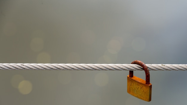 Free photo a single rusty padlock hangs on a wire.