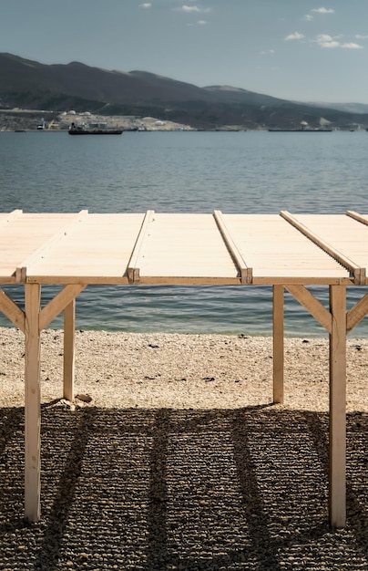 Single sun canopy stands on a pebbly beach on a sunny day City beach Black Sea coast vertical frame seaport and mountains in the background