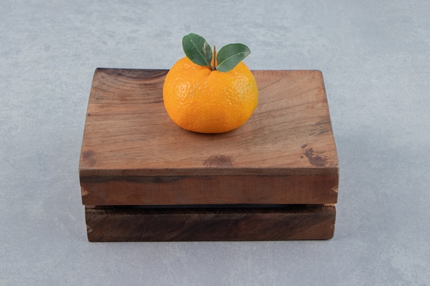 Single tasty clementine on wooden box. 