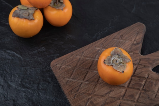 Free photo single tasty fuyu persimmon on wooden cutting board