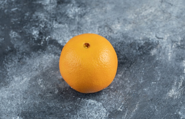 Free photo single tasty orange on marble table.