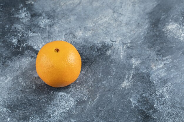 大理石のテーブルの上の単一のおいしいオレンジ。