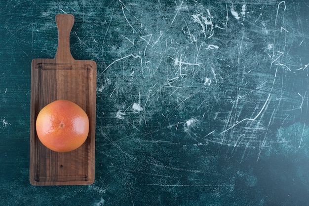 Single tasty orange on wooden board. 