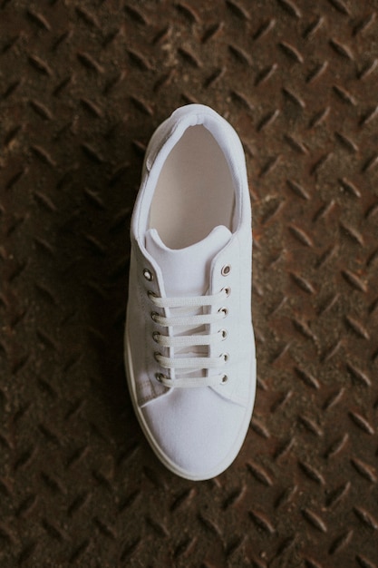 Single white canvas sneakers on metal floor