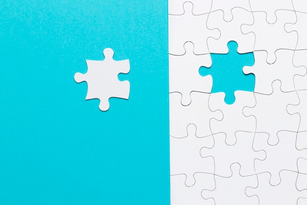 Single white jigsaw puzzle piece on blue background