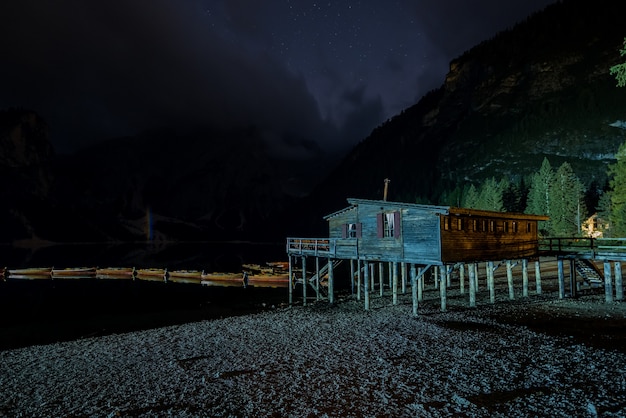 Single wooden cabin near Braies Lake in Italy surrounded by high mountains at night time