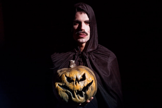 Free photo sinister man with scary pumpkin