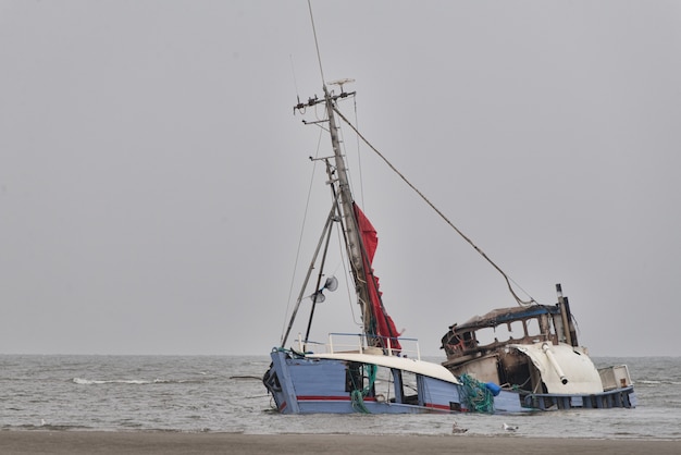 Sinking abandoned ship at the seashore under the clear sky