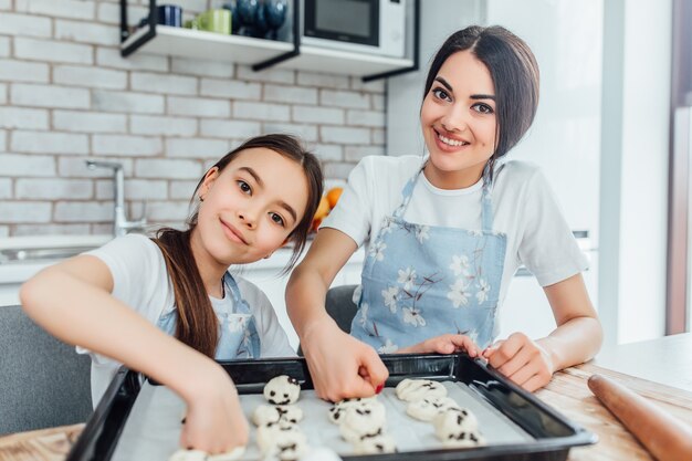 姉妹の女の子は台所でカップケーキを調理します