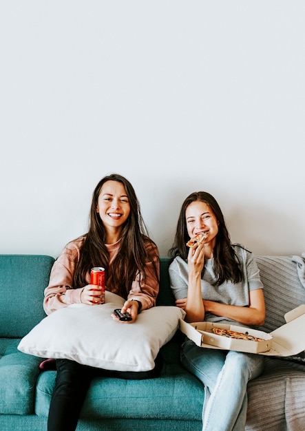 Free photo sisters eating pizza together during coronavirus quarantine