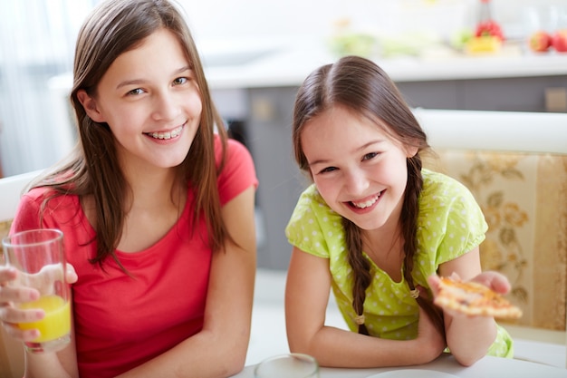 Sisters enjoying pizza and orange juice