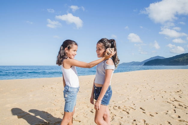 Sisters listening through seashell