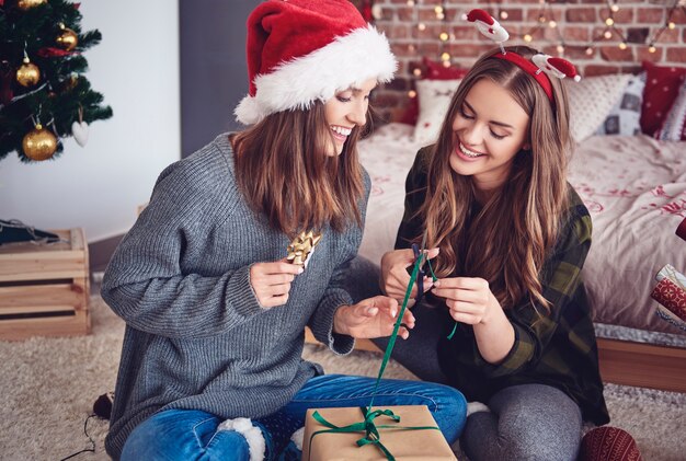 Sisters packing gifts in bedroom