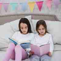 Free photo sisters reading book together