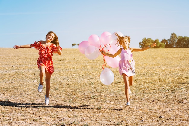 Sorelle che corrono con palloncini