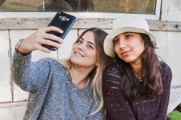 Free photo sisters taking selfie with their mobile phone