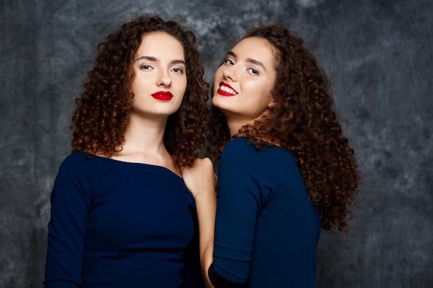 sisters twins smiling on grey