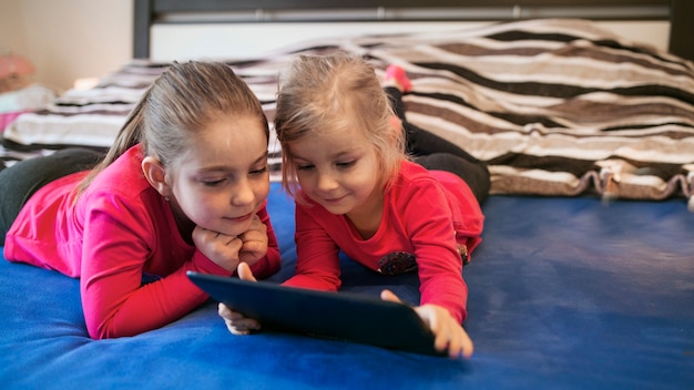 Sisters using tablet on bed