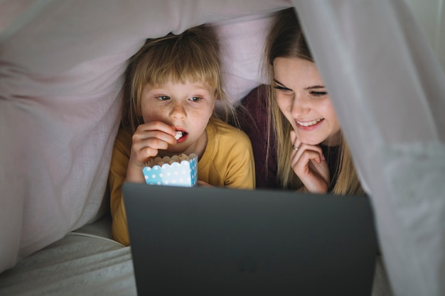 Сестры с попкорном, смотрящие фильм на планшете