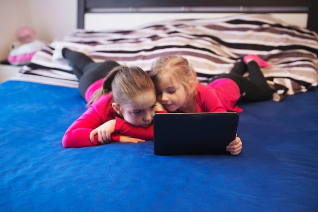 Sisters with tablet on bed