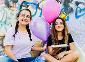 Free photo sitting friends with balloons and birthday pastry