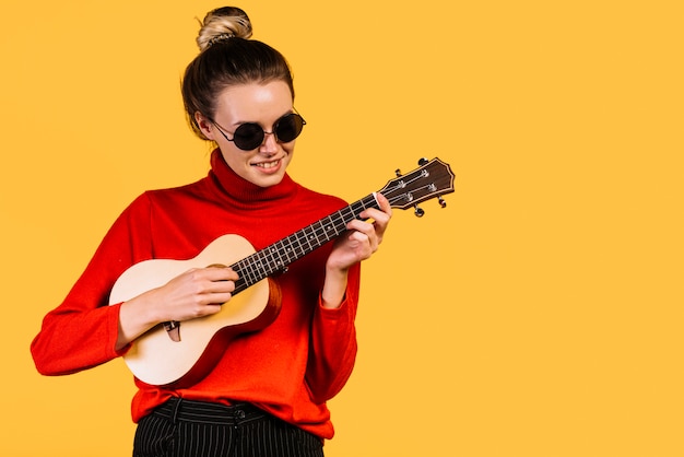 Sitting girl with glasses playing the ukelele