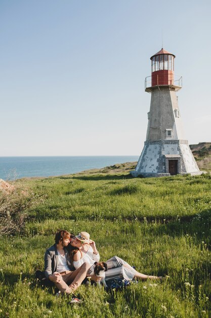 Sitting in grass young stylish hipster couple in love walking with dog in countryside