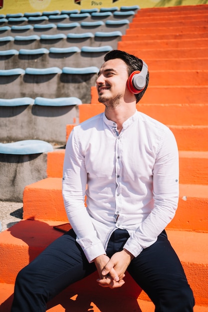 Free photo sitting man using earphones