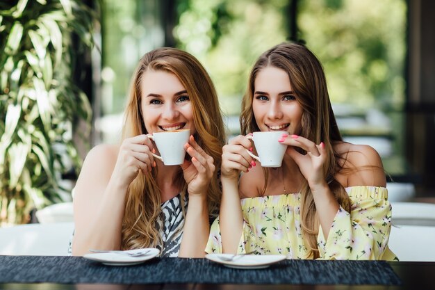 Сидящие мать и дочь пьют чай или кофе в кафе