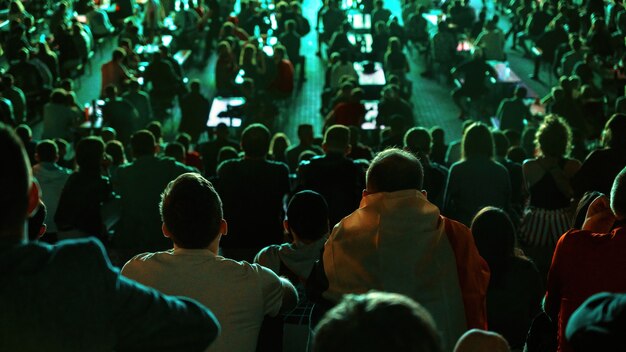 Sitting people watching football in a public place at night