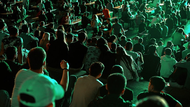 Sitting people watching football in a public place at night