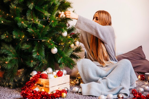 クリスマスツリーを飾る座っている女性