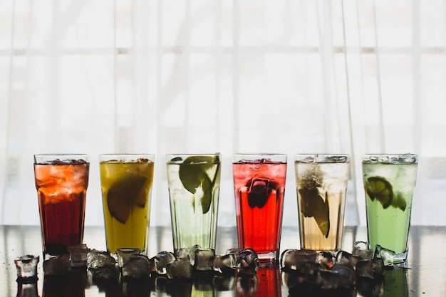 Six glasses of fruit cocktails surrounded with ice cubes