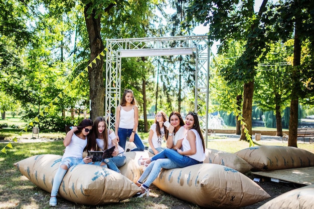 Free photo six young happy girls having fun on giant pillows in the park