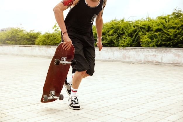 구름이 많은 날에 도시의 거리에서 트릭을하는 스케이트 보더. 운동화와 모자를 타고 아스팔트에 longboarding 젊은 남자. 여가 활동, 스포츠, 익스트림, 취미 및 운동의 개념.