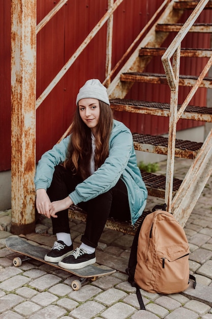 Foto gratuita ragazza di skateboarder e il suo skate in città