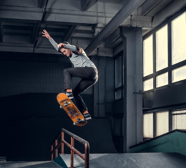 Skateboarder che esegue un trucco sulla mini rampa allo skate park al coperto.