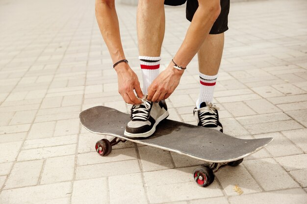 흐린 날에 도시의 거리에서 라이딩을 준비하는 스케이트 보더. 운동 화와 아스팔트에 longboard와 모자에 젊은 남자. 여가 활동, 스포츠, 익스트림, 취미 및 운동의 개념.