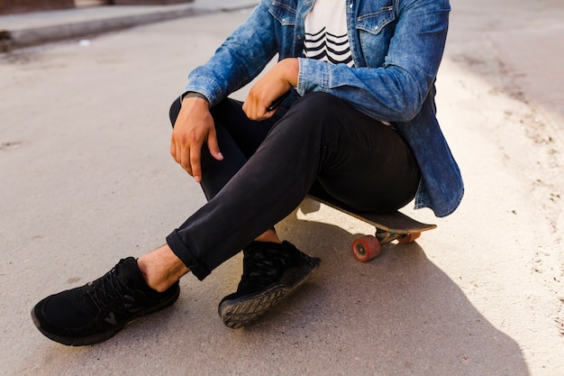 Skateboarder sitting on skateboard